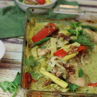Baked chicken in an oven tray with green curry sauce and baby corn