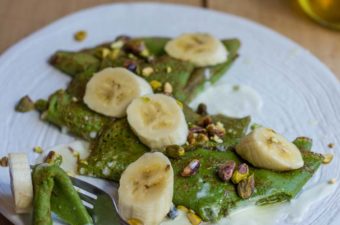 Green pancakes on a white plate with bananas