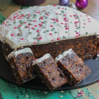 A boiled Christmas cake sliced and sitting on a plater with the rest of the cake