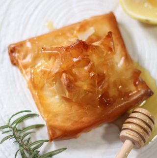 Feta baked in filo pastry with honey on a white plate