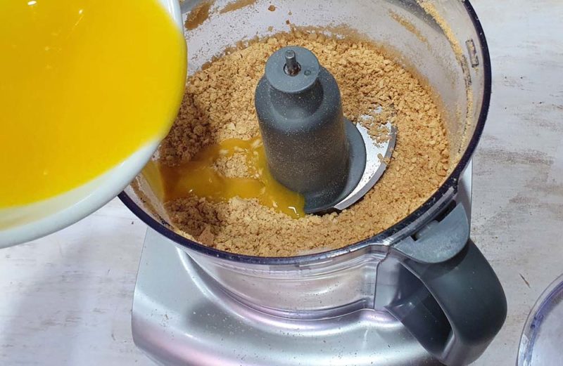 adding butter to crumbs in a food processor